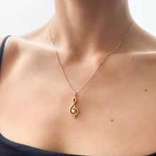 Load image into Gallery viewer, Gold necklace with a treble clef pendant on a person wearing a black top.