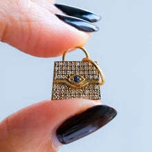 Load image into Gallery viewer, Gold handbag-shaped pendant with gemstones held between fingers against a light blue background
