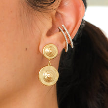 Load image into Gallery viewer, Close-up of a person wearing gold earrings with a blurred background
