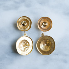 Load image into Gallery viewer, Pair of gold earrings with spiral design on a light blue background
